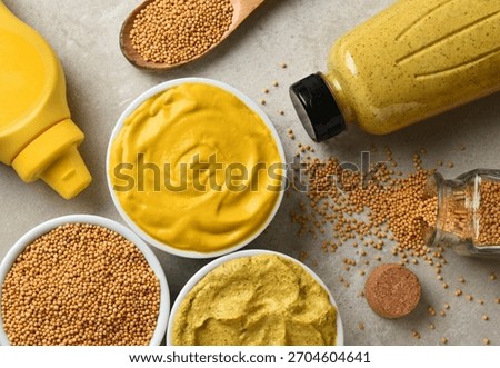 Flat lay of two different bottles of mustards in ramekins with the plastic bottles and mustard seeds. No labels on the bottles.