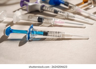 плоский лежак из различных шприцев, ампул, медицинских перчаток, одноразовой шапочки, светлого фона, естественного солнечного света. Концепция медицинского препарата или косметическая процедура установки