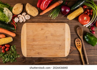 Flat lay of vegetables and food and a chopping table over a wooden table