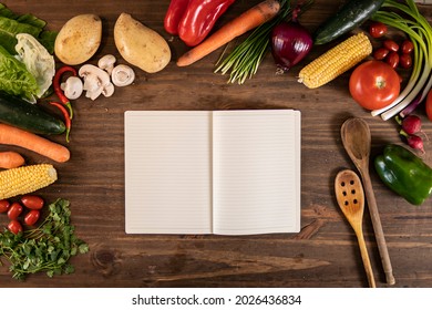 Flat lay of vegetables and food and an empty notebook over a wooden table