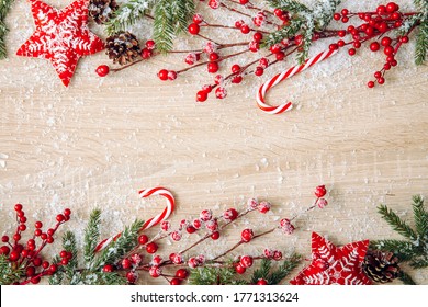 Flat lay view of Christmas frame background. Branches with red berries, felt star ornaments, red candy canes and spruce branches, copy space.