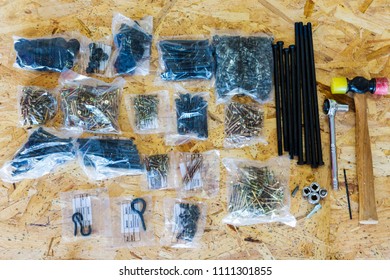 Flat Lay View Of Hammer, Screws With Woodworking Accessories Against Plywood Background