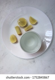 Flat lay view of lime slices and a glass of water on white plate and marble surface , a new normal morning routine and food combining lifestyle