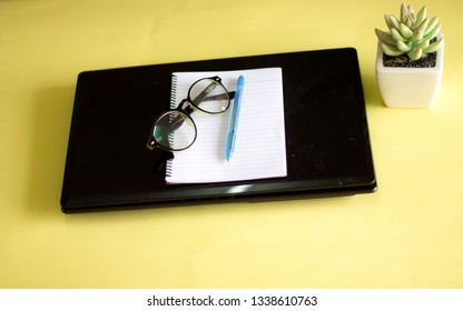 Flat lay view of office table desk. Workspace with keyboard, pen, book, coffee and decoration flower on yellow background. Copy Space concept