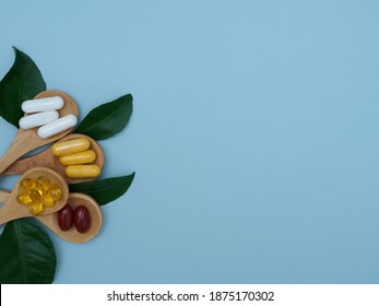 Flat lay of vitamins, minerals, pills in wooden spoons and green leaves on a light blue background with copy space, top view. Integrative medicine. Medicines to improve immunity - Shutterstock ID 1875170302