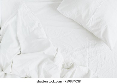 Flat lay of white bed with pillows, blanket and sheet. Top view minimal linen concept. - Shutterstock ID 759874039