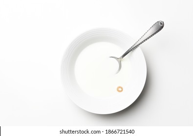 Flat Lay White Cereal Bowl With Spoon And One Piece Of Cereal Floating In The Milk. High Key Still Life With Copy Space.