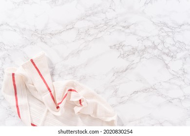 Flat Lay. White And Red Kitchen Towel On A Marble Kitchen Counter.