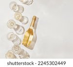 Flat lay with white sparkling wine bottle, set glasses wine with sunshine shadow and flare on light beige background. White wine aesthetic photo, copyspace. Summer holiday monochrome color still life