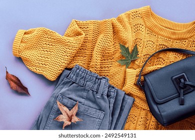 Flat lay of woman's yellow sweater, gray jeans, bag and autumn leaves. Autumn fashion concept. Top view, flat lay. - Powered by Shutterstock