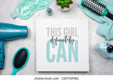 Flat lay of women's beauty products with inspirational quote that says "This girl definitely can" - empowerment concept - Powered by Shutterstock