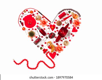 flat lay of women's gizmos in the shape of a red heart - beads, lipstick, hairpins, perfume, rings, candies, beads and pomegranate seeds - Shutterstock ID 1897970584