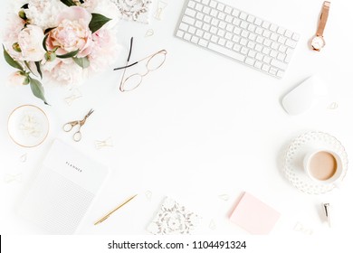 Flat lay women's office desk. Female workspace with computer, pink peonies bouquet, accessories on white background. Top view feminine background.