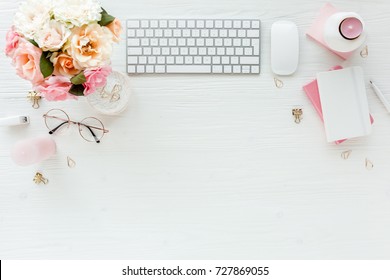 Flat Lay Women's Office Desk. Female Workspace With Computer, Pink Roses Flowers Bouquet, Accessories, Golden Diary, Glasses On White Wooden Background. Top View Feminine Background.