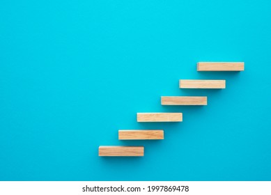 Flat Lay Of Wooden Blocks In Shape Of Staircase Step On Blue Background With Copy Space. Growth Or Development Step By Step For Successful In Business Financial Or Education Concept.