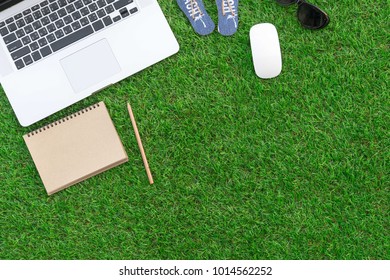 Flat lay work concept with computer laptop and travel accesories on  grass floor while a trip travel in holidays