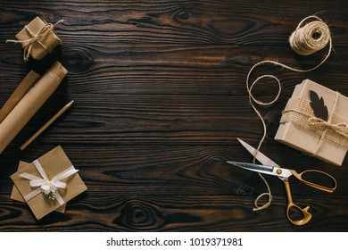 flat lay with wrapped presents, rope and scissors on wooden surface