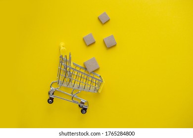 A flat layer of brown boxes falling into the basket on a yellow isolated background. Close-up, copy space