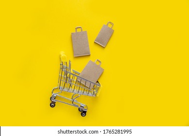A flat layer of brown paper shopping bags for groceries falling into the shopping cart. Close-up, yellow isolated background