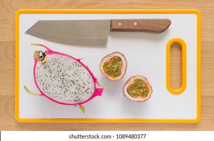 Flat Lay/Flatlay Of A White Dragon Fruit And A Cut Passionfruit With A Knife On A White Cutting Board. 