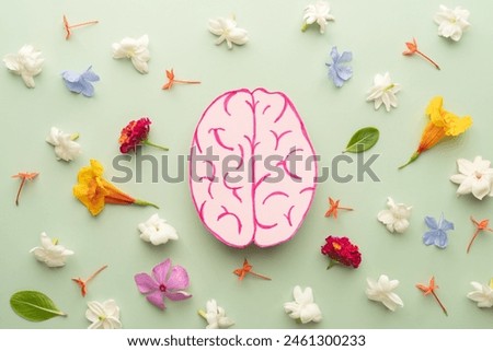 Flat layout of human brain anatomy with colorful fresh flower on green background. Mental health care, positive thinking and creative idea concept.