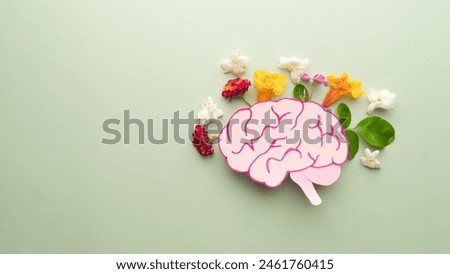 Flat layout of human brain anatomy with colorful fresh flower on green background. Mental health care, positive thinking and creative idea concept.