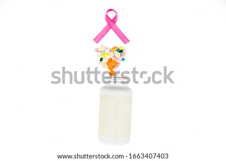 Flat layout of pink ribbon, heart shaped pills, and a medicine bottle in a straight line, isolated in white background