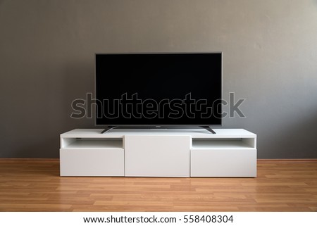 Flat LCD television on white cabinet in the living room with dark gray wall and parquet floor