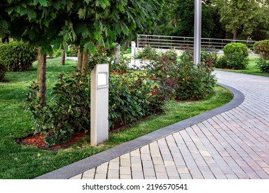 Flat Led Lantern Of Ground Garden Lighting With Roses Flowers In Backyard With Mulch Flower Bed And Green Turf Lawn Lit By Sunset Light Landscape Near Stone Tile Walkway With Granite Curb, Nobody.