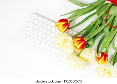 Flat lying Valentine's Day background with computer keyboard and tulip bouquet. Spring top view.