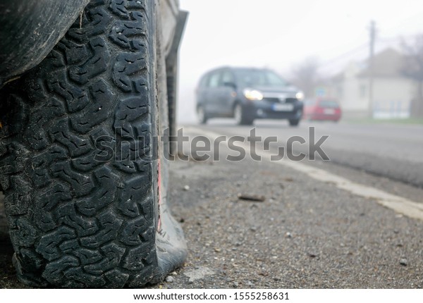 Flat off road tire on focus, moving cars on\
the blured background.
