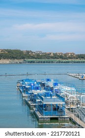 Flat Party Boats On A Dock At Lake Austin, Austin, Texas. There Is A View Of Large Residential Buildings On Top Of The Slope Across The Lake.