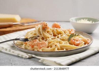 Flat plate with pasta spaghetti with heavy cream and roasted shrimps with garlic sauce and parmesan cheese on concrete surface