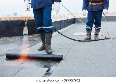 Flat roof installation. Heating and melting bitumen roofing felt 