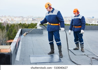 Flat roof installation. Heating and melting bitumen roofing felt