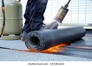Flat roof installation with propane blowtorch during construction works with roofing felt. Heating and melting bitumen roofing felt. Roofing felt. Roofer working. Roofer working tool. Waterproofing - Shutterstock ID 1471821653
