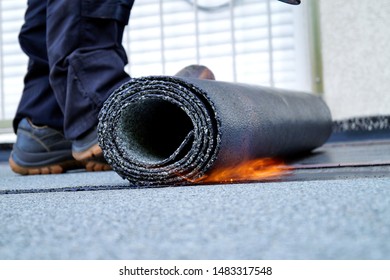 Flat roof installation with propane blowtorch during construction works with roofing felt. Heating and melting bitumen roofing felt. Roofing felt. Roofer working. Roofer working tool. Waterproofing
