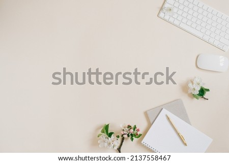 A flat scene in beige tones for a self-employed freelance girl. Planner, pen, computer and white apple flowers. Sketchy notebook or notebook mockup.