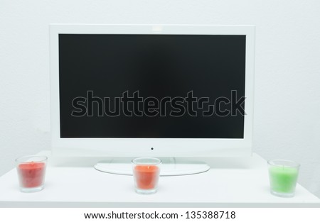 Flat screen television on table with colourfful candles