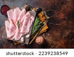 Flat slices of square sandwich ham with herbs. Dark background. Top view. Copy space.
