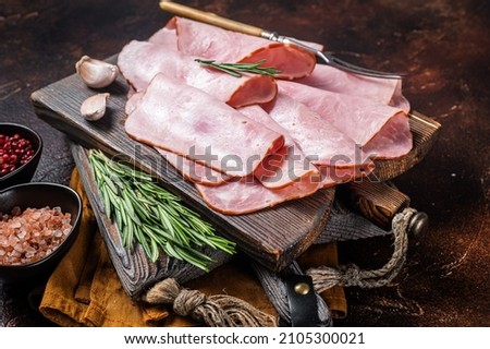 Flat slices of square sandwich ham with herbs. Dark background. Top view
