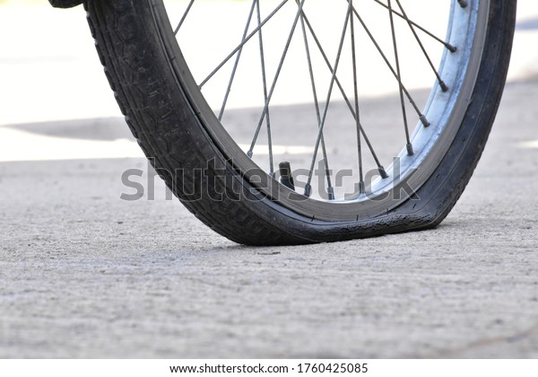 \
The flat tire of a bicycle is parked on the side\
of the road.