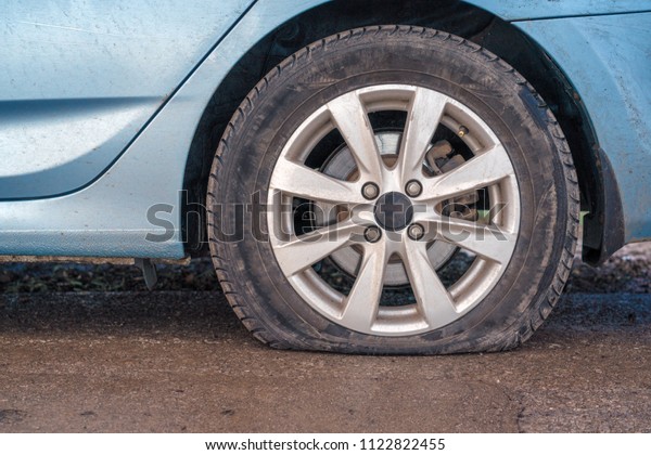 Flat tire\
of blue car on the road waiting for\
repair