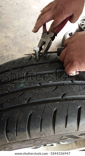 Flat tire. Nails prick into tires. The process of\
pulling a nail out of a\
tire.
