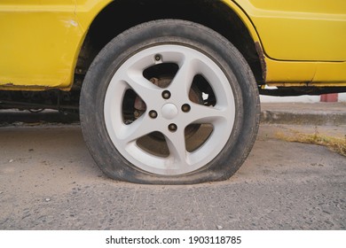 Flat tire of an old car yellow, the body of the car starts to rust.Repair is not worth it.