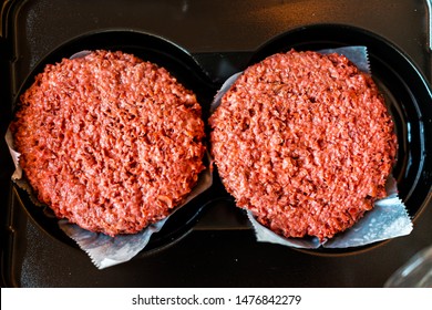 Flat Top Closeup Of Two Raw Uncooked Red Vegan Plant Based Meat Burger Patties In Packaging