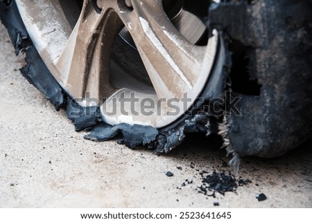 Flat and torn front left tire of the car in close-up. An insured event is a traffic accident, a tire puncture. The vehicle is standing on a road with perforated rubber on a wheel with a metal disc