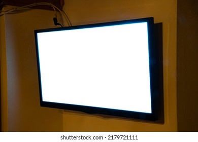 A Flat TV Set Mounted On The Wall Of A Room. Angled Shot, Pure White Screen.
