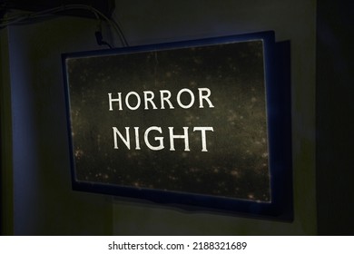 A Flat TV Set Mounted On The Wall Of A Room, Showing The Intertitle From An Old Silent Film With The Text Horror Night. Angled Shot.
