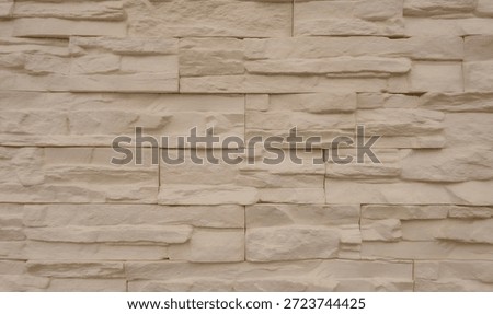 A flat wall surface covered with decorative cream color gypsum tiles that look like stone
